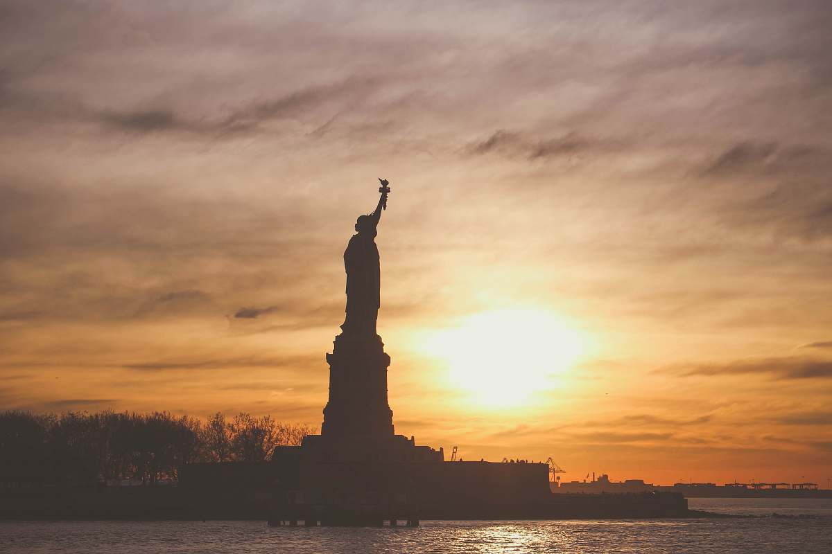 new york silhouette photo of Statue of Liberty during golden hour sunset